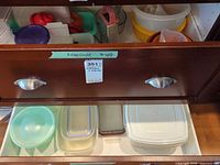 Drawer view showing mixing bowls, salad spinner, grater, strainer, funnels, plastic containers and lids