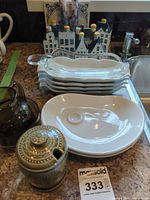 Group shot of Delft houses, trivet, candles, corn dishes, glass gravy boat, smoked glass pieces, white plates, Irish sugar bowl