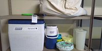 Coleman cooler, Coleman jug, air mattress bag, pitchers, bowls, plates visible