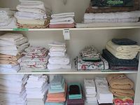Stacks of folded sheet sets, pillowcases and assorted towels on shelving