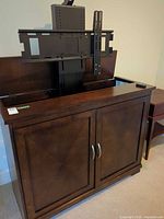 Full view of dark brown motorized TV lift cabinet with doors closed and lift extended showing bracket