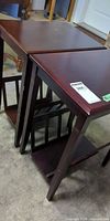 Pair of matching dark reddish-brown end tables, angled view