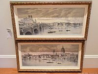 Two framed chromolithograph cityscape prints stacked against wall
