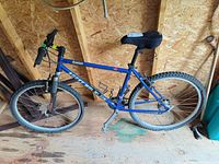 Full left-side view of blue Rocky Mountain Fusion mountain bike in shed