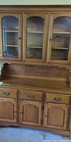 Full view of two-piece maple china cabinet with glass-door hutch and lower storage