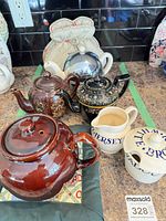 Group of assorted teapots, jug and cozy on countertop