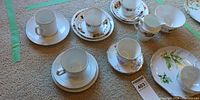 Lot overview showing multiple tea cup and saucer sets on carpet