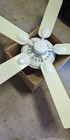 Top view of ceiling fan showing five white blades attached to motor housing