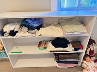 Front view of white three-shelf unit with items on shelves (contents not included)