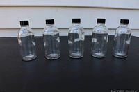 Front view of five clear glass vials with caps
