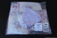 Sealed plastic package showing folded layette pieces and top hat