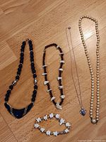All five jewelry pieces laid out on wood surface