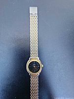 Full view of Omega wristwatch with two-tone link bracelet laid flat