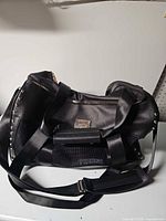 Overall view of black Badgley Mischka soft-sided pet duffle with shoulder strap and mesh sides