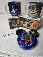 Overall lot view: two boxed mugs and handheld trivia game