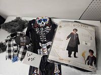 Overall view of three costumes: sealed Harry Potter package, infant Day of the Dead suit, pet werewolf costume