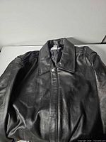 Full view folded black leather Pepsi jacket showing collar and front
