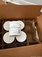 Open shipping box with eleven Alexandria Professional sugaring paste jars in cardboard dividers