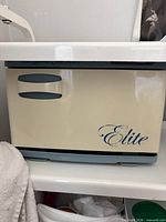 Front view of Elite cream hot towel cabinet on shelf
