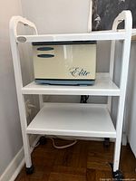 Full view of white metal Silhouet-Tone two-shelf trolley on casters; device on shelf not included