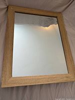 Front view of rectangular mirror showing light wood frame and reflective surface