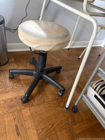 Full view of stool showing beige seat, black five-caster base