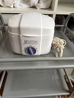 Front view of Satin Smooth wax warmer showing brand logo, control dial, and power cord