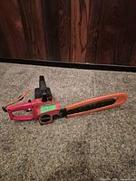 Left side view of Craftsman electric chainsaw showing full bar with orange scabbard and brand badge