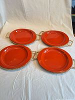 Top view of four coral plates with wicker handles