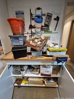 Overall lot showing bench vise, workbench, pegboard, bins, hardware