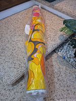 Full length of rolled fabric in plastic, showing psychedelic print