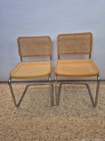 Front view of both cantilever chairs showing cane seats and backs