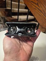 Front view of Turtle folding opera glasses showing brand logo on black housing