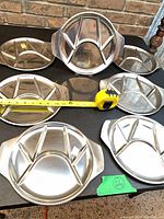 All seven stainless steel divided plates with measuring tape showing diameter