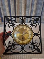 Front view of square cast iron wall clock with brass dial