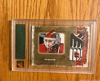 Front view of factory-sealed Ed Belfour Ultimate Gold jersey patch card showing photo, patch window and serial numbering