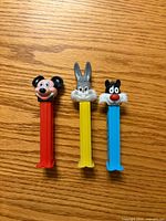 Front view of three Pez dispensers showing character heads and stem colors