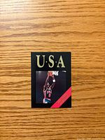 Front of Michael Jordan Olympic card showing image, USA text, red name banner
