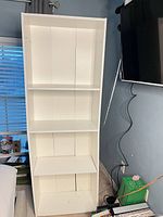 Front view of white melamine bookcase showing four shelves and missing backing panel