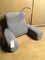 Front view of gray reading pillow showing armrests and attached gooseneck LED lamp