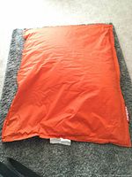 Full view of orange Fatboy beanbag lying flat