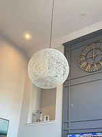 Full view of spherical white string pendant lamp hanging from ceiling