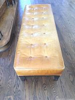 Full view of tan leather bench on wood floor