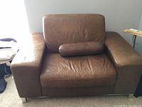 Front view of leather oversized chair showing pillow and seat