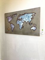 Full view of rectangular metal world map wall art hanging on wall