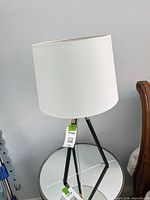 Full view showing white drum shade and black tripod base