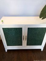 Front view of white cabinet with green glass panel doors
