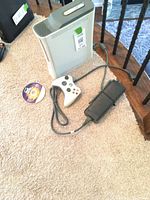 White Xbox 360 console, controller, power supply, Guitar Hero disc on carpet