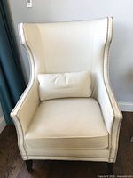 Front view of white leather wingback chair with lumbar pillow