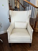 Front view of white leather wingback chair with lumbar pillow